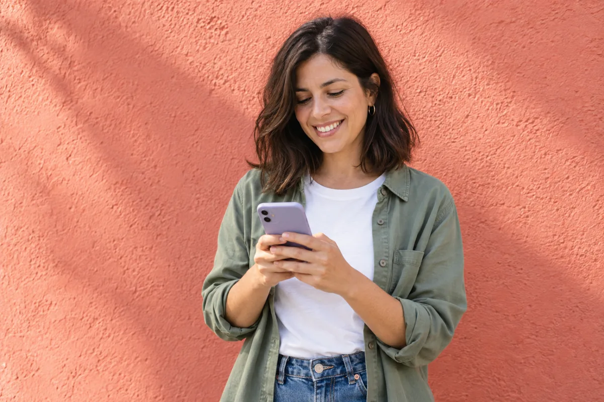 Mujer sonriendo mientras usa su teléfono